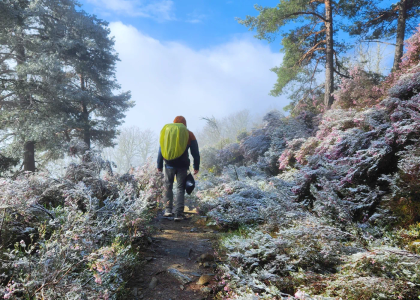 A man hiking in the mountains, freezing temperature in may, frost covered flowers.